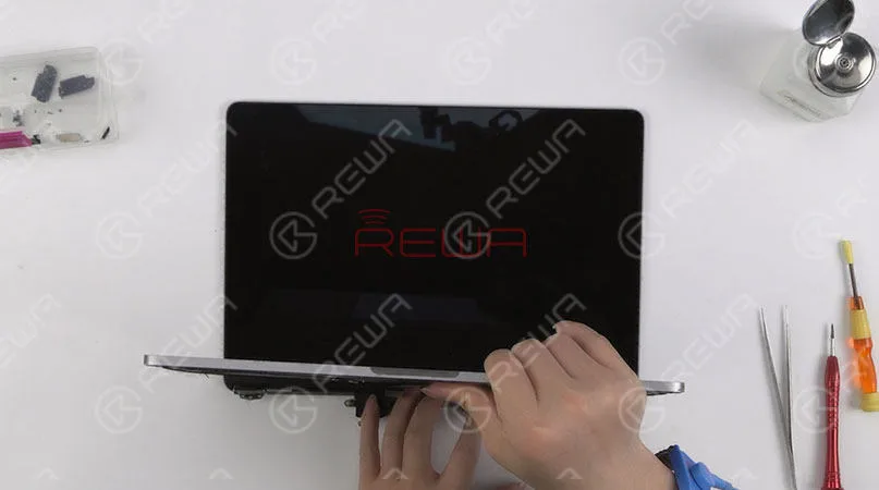 Una vez hecho esto, instale la barra de resorte. Apriete los tornillos que fijan la barra de hierro de la pantalla y luego consiga la tira del LOGO adherida. Ensamble la pantalla y la mitad inferior del teclado. Continúe con la instalación de la antena WiFi y la fijación del cable flexible de la pantalla. Apriete los tornillos que fijan la antena WiFi y la pantalla. Una vez terminado, conecte la batería e instale la carcasa inferior. 