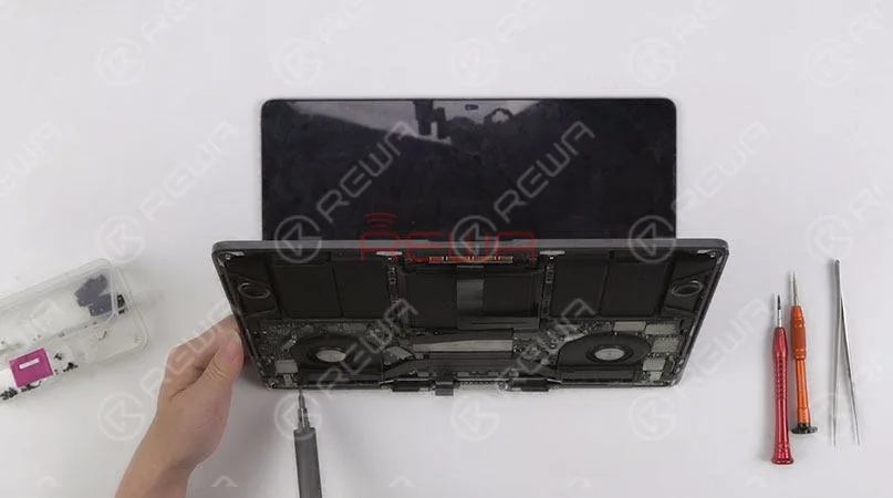 Continúe retirando los tornillos que fijan la pantalla. A continuación, separar el conjunto de la pantalla de la mitad inferior del teclado. 
