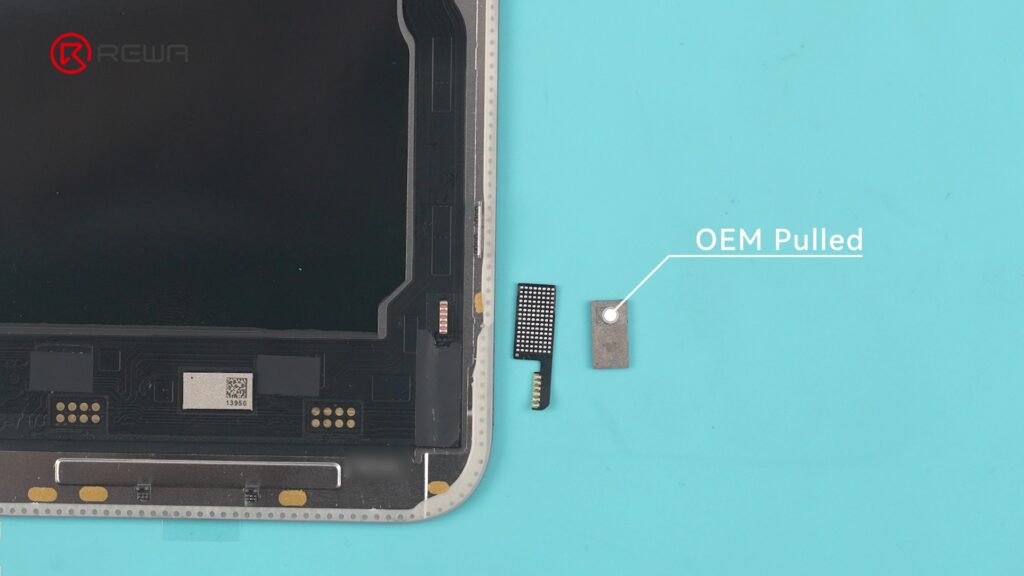 Un chip rectangular pequeño etiquetado como OEM Pulled al lado de un ensamblaje de pantalla de iPhone