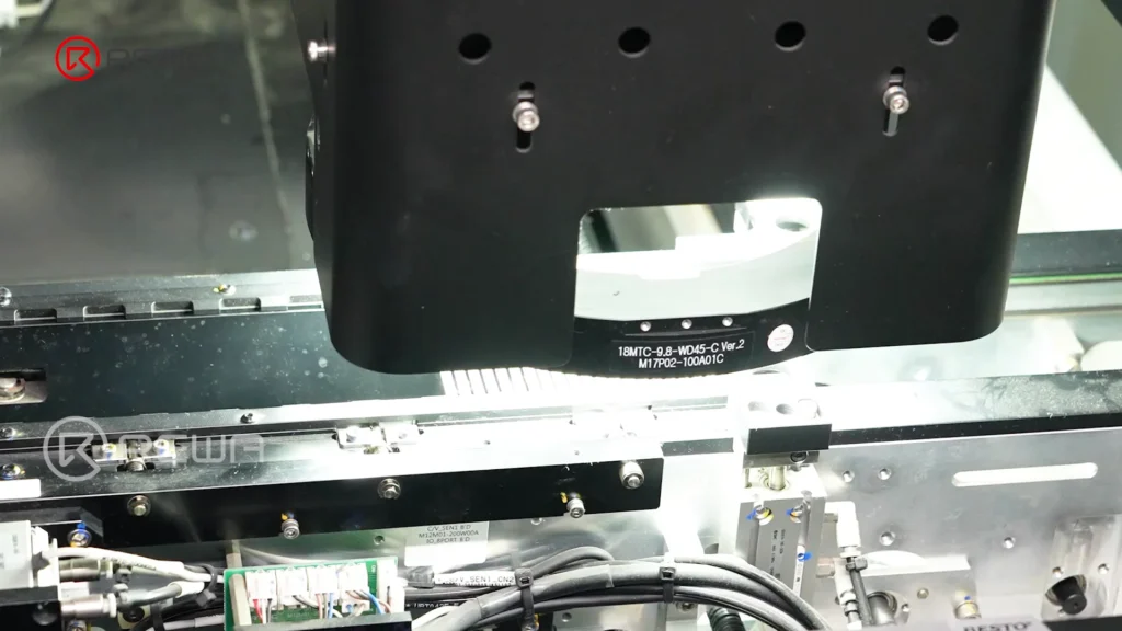 Automated optical inspection machine head scanning circuit boards under bright light on an assembly line